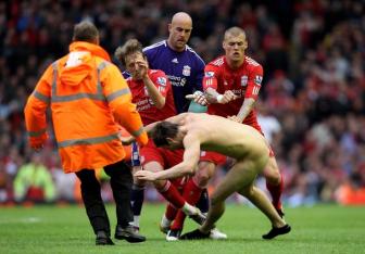 streaker on the pitch is bundled over by Lucas, Pepe Reina and Martin Skrtel of Liverpool